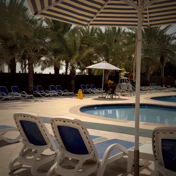 Cover Not The End of the World (Remix): striped parasol and loungers at the pool of Al Hamra Residence, footage by Kay