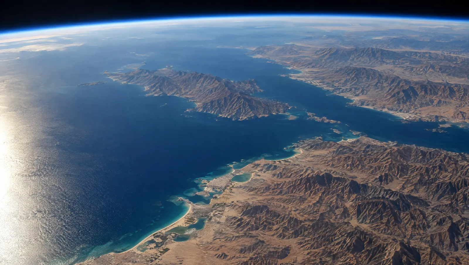 The Musandam peninsula and the coast of Ras Al Khaimah seen from orbit, afternoon light on the Gulf. AI-generated image.