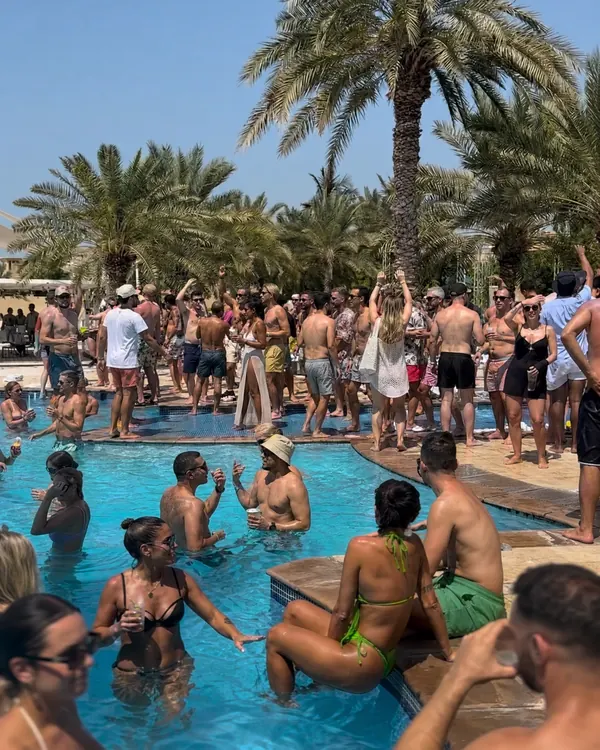 Guests celebrating in and around the pool on a sunny afternoon. AI-generated image.
